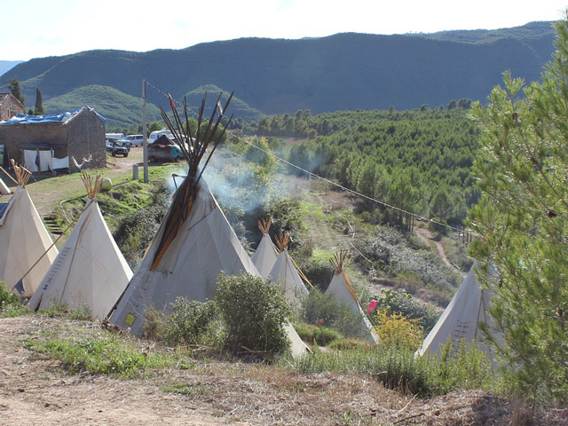 Mehrere Tipis am Rand eines Berges aufgestellt.